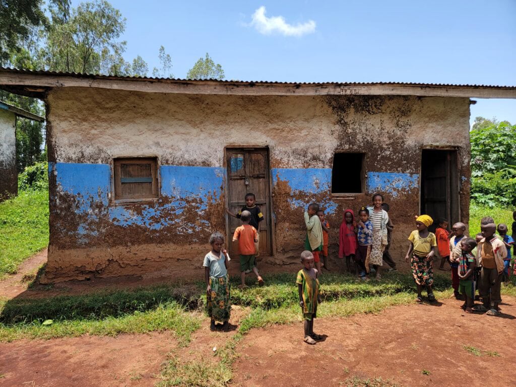 Children gathered outside a rustic, eco-friendly school building in Ethiopia, promoting education and community development.